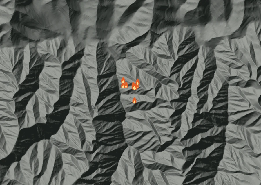 Shaded relief map of the Monument Fire. Amber flames mark every place that gave off heat in the last day; the shading is the shape of the ground.