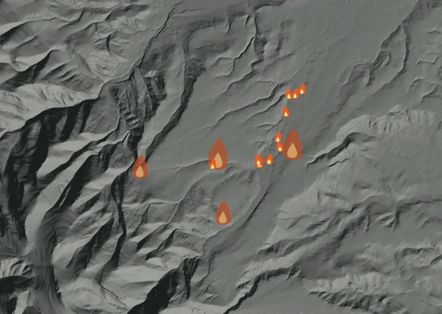 Shaded relief map of the Pk Fire. Amber flames mark every place that gave off heat in the last day; the shading is the shape of the ground.